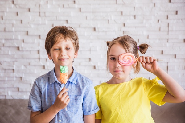 Adorable smiling little girl and boy holding colorful sweet meringues on a stick on Easter day